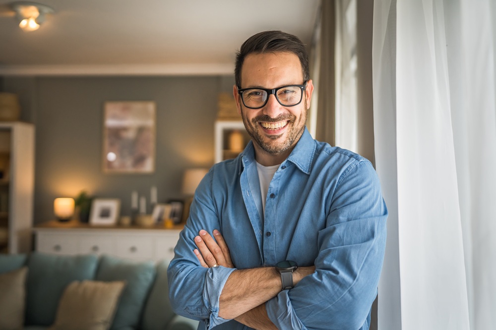 Smiling man standing near a bright window, representing comfortable dental care for adults in the Los Angeles community